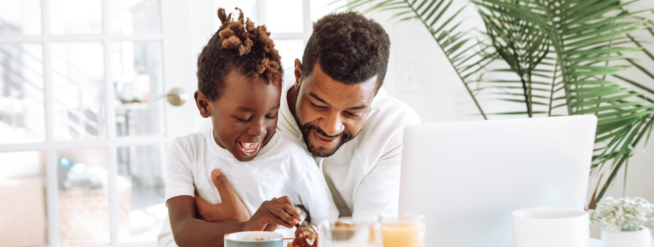 Father and child having lunch in front of their laptop